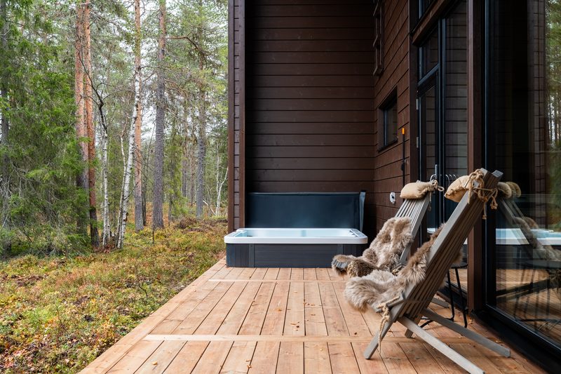The outdoor jacuzzi open on the timber deck with a fur-draped chair beside it.