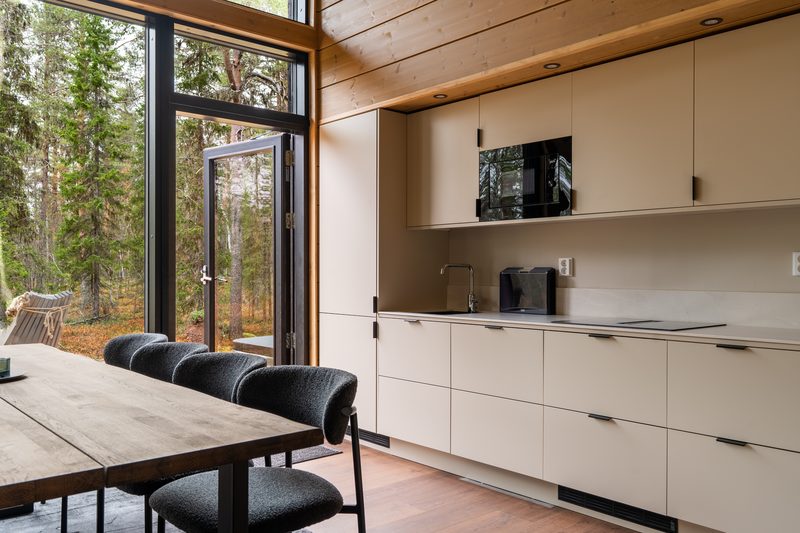 The full run of kitchen cabinetry with worktop, microwave and tall units, and the dining table in front of it.