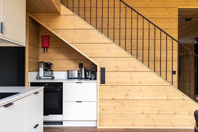 The kitchen tucked under the staircase, with the oven, coffee machine and kettle on the worktop.